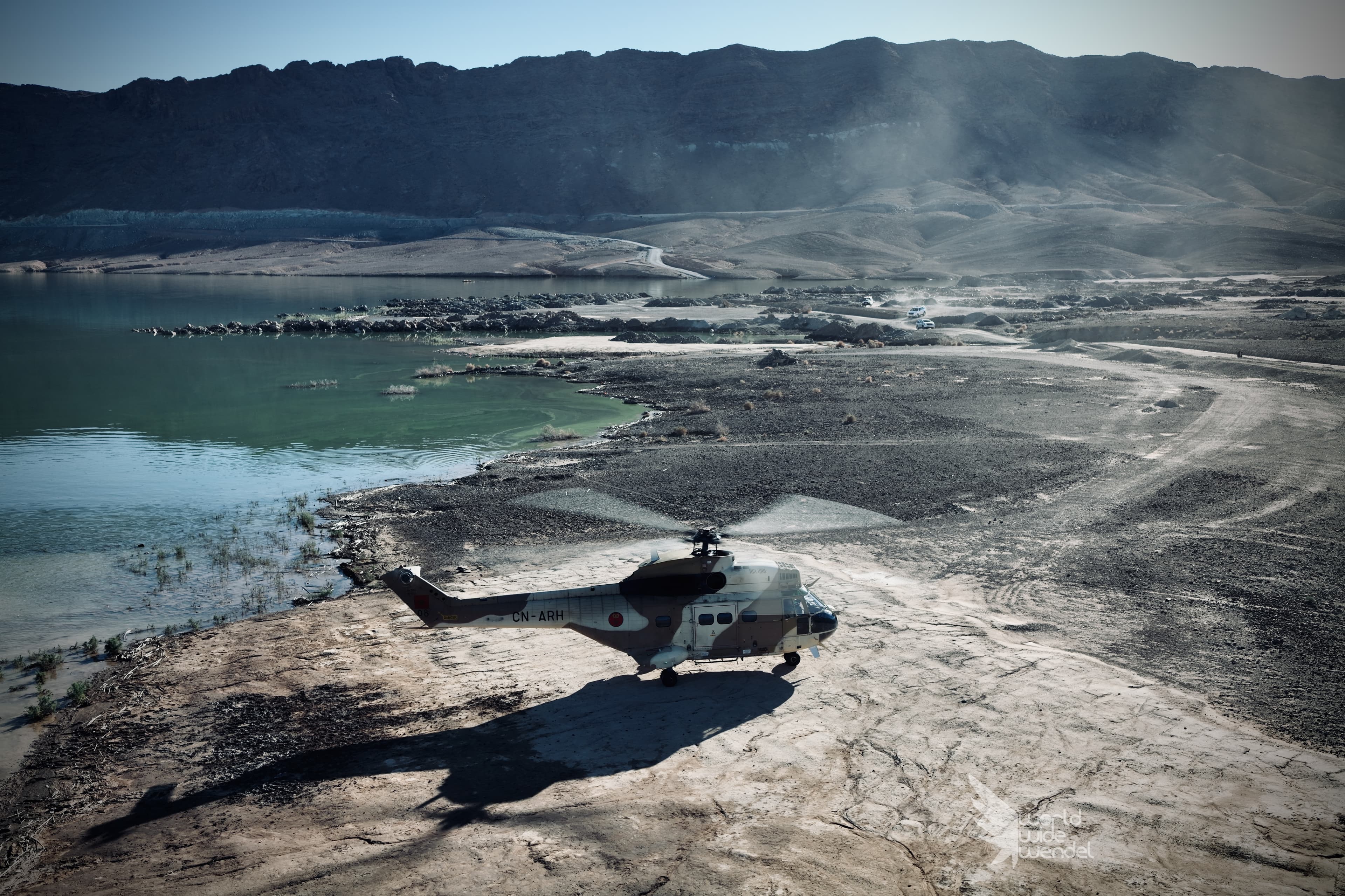 Een legerhelikopter aan de oever van een meer in de bergen
