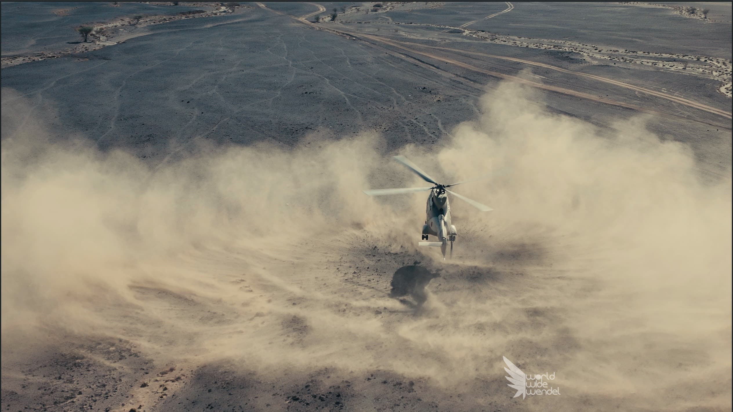 Een helikopter die opstijgt in een stofwolk in de woestijn