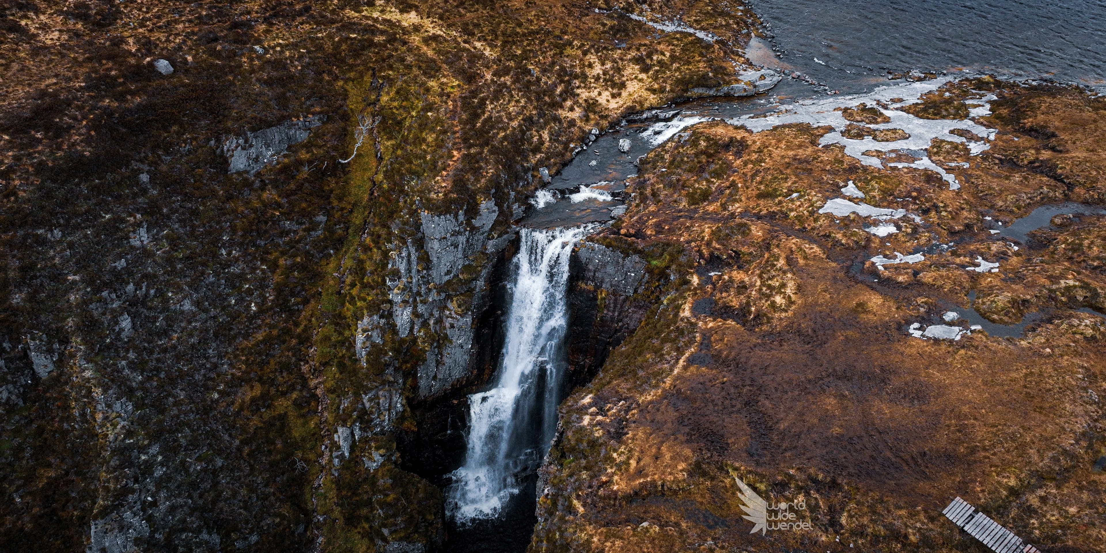 Luchtfoto van een waterval die van een rotsachtige klif de zee in stort